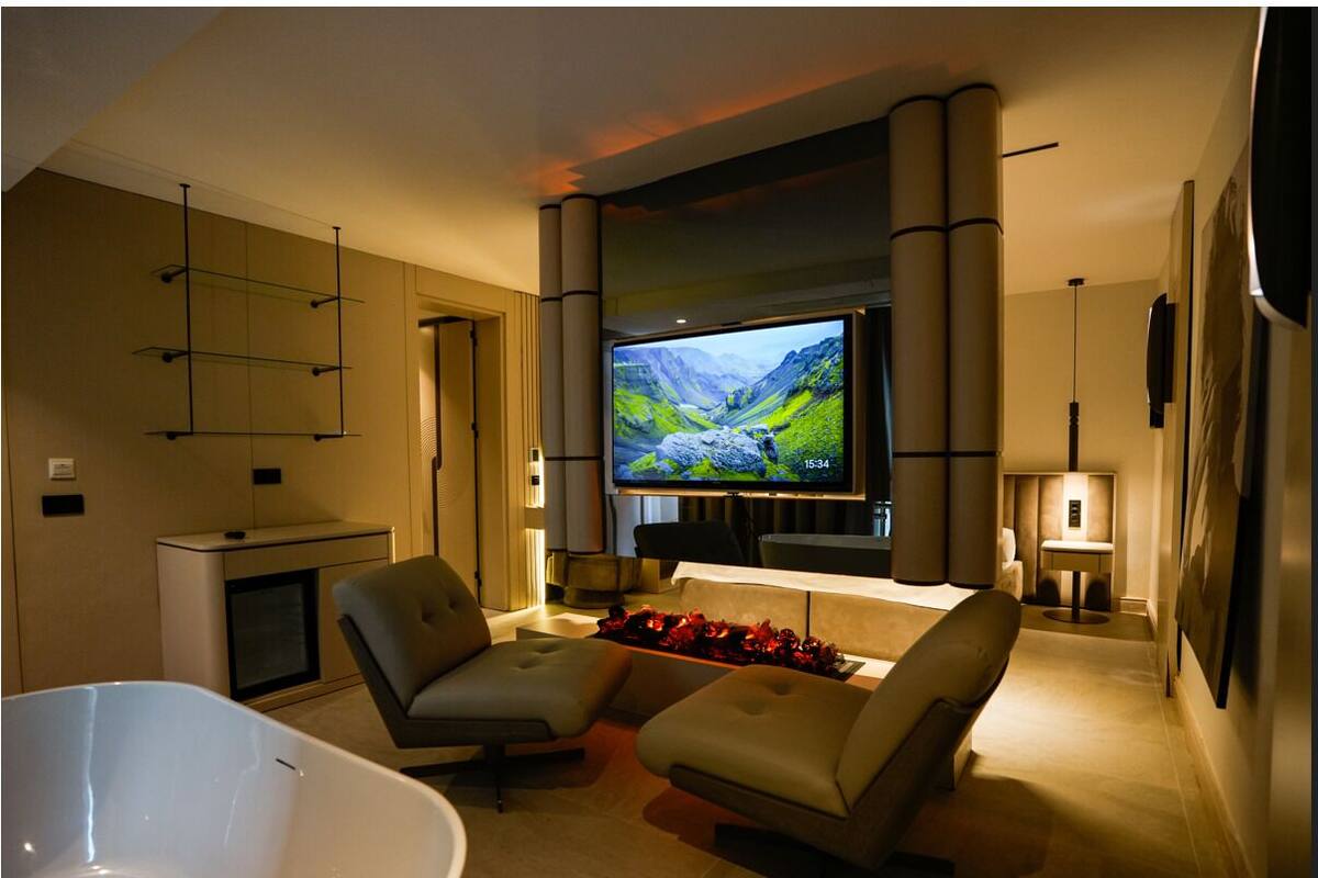 A modern living room with a flat-screen TV, two sofas, a white bathtub, and a fireplace.