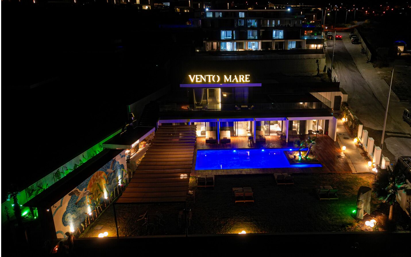 A hotel with a pool, outdoor seating, and a sign reading 'VENTO MARE'.