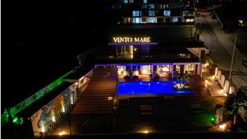 A hotel with a pool, outdoor seating, and a sign reading 'VENTO MARE'.