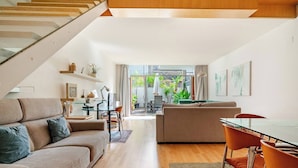 Ein modernes Wohnzimmer mit einem Glastisch, zwei Sofas und einer Treppe.