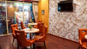 A dining area with a round table, orange chairs, and a wooden accent wall. - Belvilla Luxury Phoenix East Beach (Dubai)