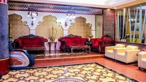 A luxurious lobby with red sofas, a patterned carpet, and a decorative wall with intricate designs. - Belvilla Luxury Phoenix East Beach (Dubai)