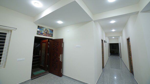A hallway with a wooden door, a small window, and a ceiling light. - Perambalur Villa  (Perambalūr)