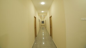 A long, narrow hallway with cream-colored walls and a shiny, reflective floor. - Perambalur Villa  (Perambalūr)