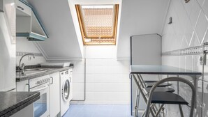 Una cocina compacta con lavadora, un lavamanos y una pequeña mesa con sillas.