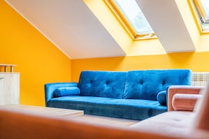 Quarto com sofá azul, um armário de madeira e janela com vista.
