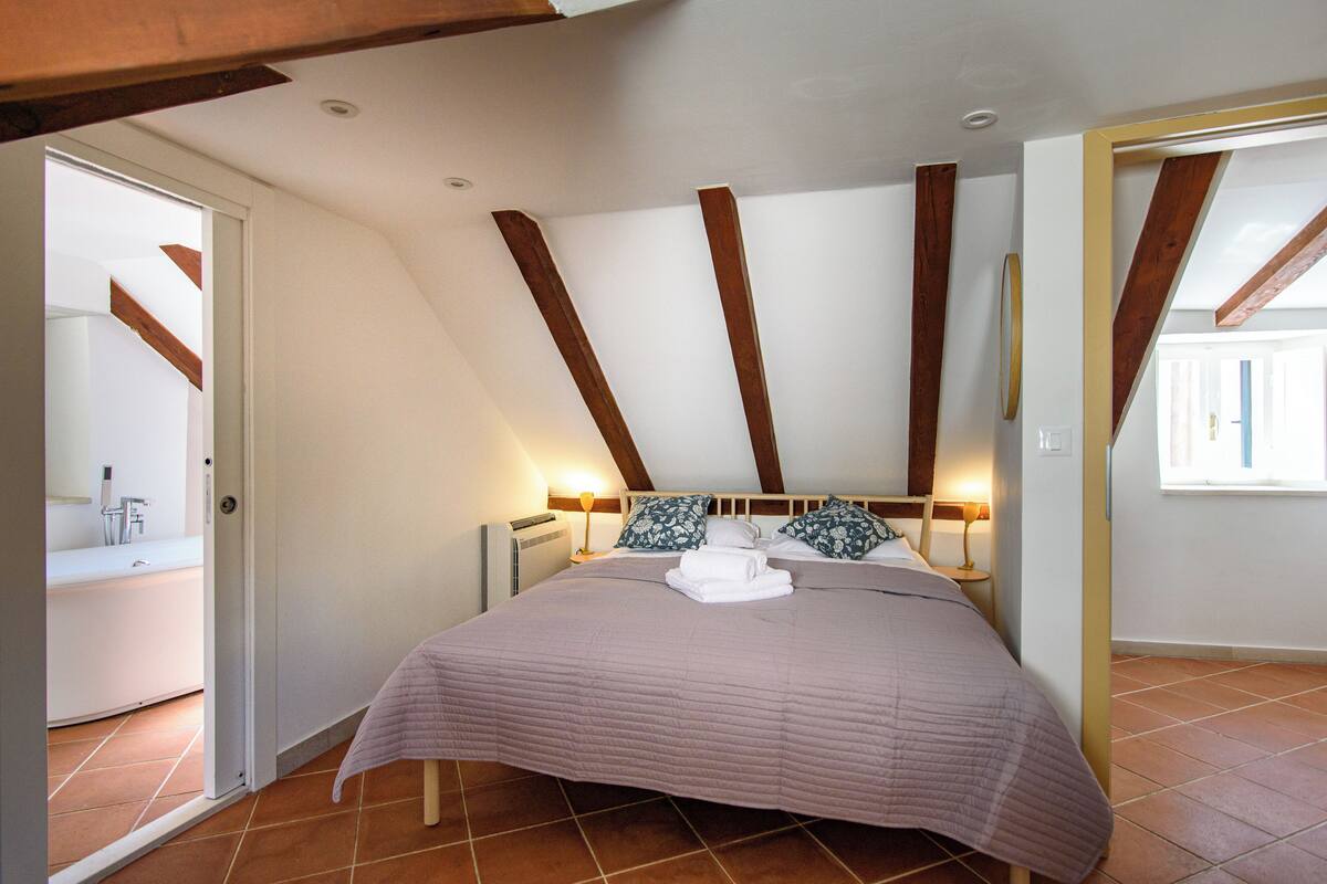 Un dormitorio con cama, mesitas de noche y una ventana.