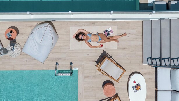 An aerial view of a pool area with a lounge chair, a sun lounger, and a table with a drink. - Villa Quercus, Aesthete Villas (Rethymno)
