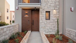 A modern building with a stone facade, a wooden double door labeled "QUERSUS," and a small balcony with a metal railing. - Villa Quercus, Aesthete Villas (Rethymno)