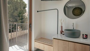 A modern bathroom with a large round mirror, a round sink, a towel rack, and a view of trees through the window. - Villa Quercus, Aesthete Villas (Rethymno)