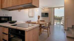 A modern kitchen with wooden cabinets, a built-in microwave, and a dining area with a table and chairs. - Villa Quercus, Aesthete Villas (Rethymno)