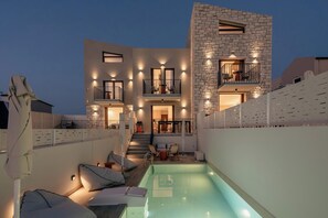 Un bâtiment moderne à deux étages, doté d’une piscine, d’un espace extérieur aménagé et d’un escalier menant à l’étage supérieur.