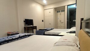A hotel room with a bed, a desk with a computer, a wardrobe, and a television. - Saryu Homestay (Ujjain)