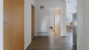 A hallway with wooden flooring, white walls, and a door leading to a dining area. - Apartment 'Family Küstenbrise' with Wi-Fi (Heide)