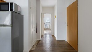 A hallway with a refrigerator, microwave, and a wooden door. - Apartment 'Family Küstenbrise' with Wi-Fi (Heide)