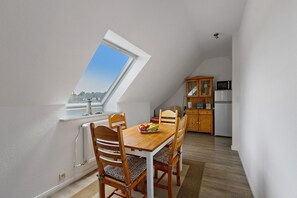 A dining area with a table, chairs, and a fruit bowl. There is a kitchen in the background with cabinets and appliances. - Apartment 'Family Küstenbrise' with Wi-Fi (Heide)
