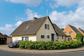 Un immeuble résidentiel doté d’un toit en pente, d’une porte de garage visible et d’une voiture garée devant.