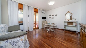 Een woonkamer met een bank, een eettafel met stoelen, een televisie en een spiegel.