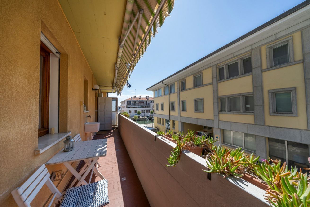 A balcony with a table and chairs, potted plants, and a view of adjacent buildings.