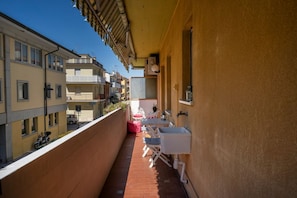 Un balcon étroit avec un évier blanc, une chaise et une petite table.