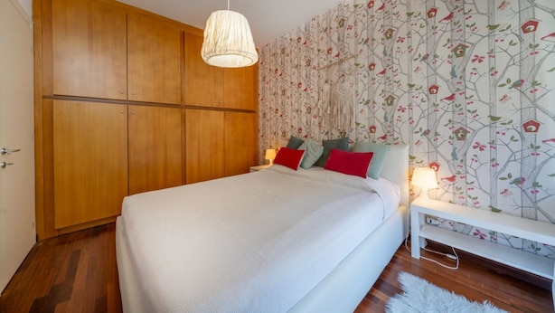 Een slaapkamer met een groot bed, een houten garderobe en bloemenbehang.