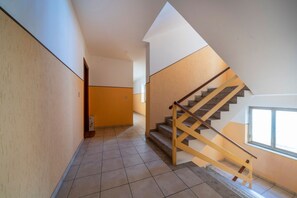 Eine Treppe mit Holzbalkonen und Fliesenboden, die zu einem Raum mit einem Fenster führt.