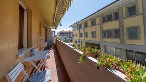 A balcony with a table and chairs, potted plants, and a view of adjacent buildings. - GuestHost - Cozy 53 sqm apartment, perfect for four people, located on the first floor of a building with an elevator (NOT accessible to disabled guests).The property is located in Grado, known as the Island of the Sun, a beautiful lagoon town famous for (Grago GO)