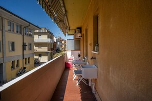 A narrow balcony with a white sink, a chair, and a small table.