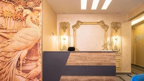 A reception desk with a wooden finish, flanked by ornate wall carvings and framed mirrors. - Settle Inn South 90 Apartments (Cairo Governorate)