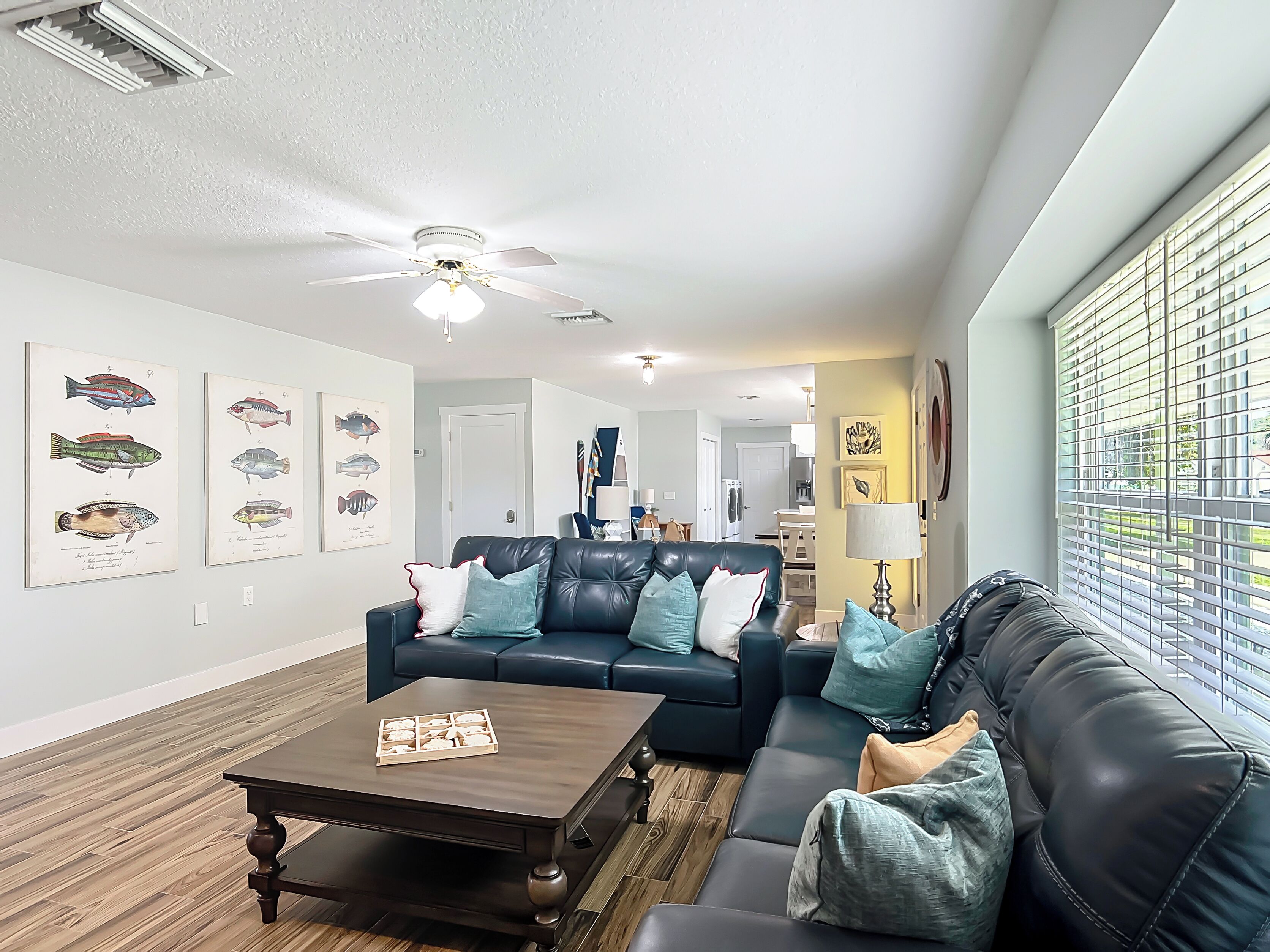 A modern living room with a dark leather sofa, a wooden coffee table, and a ceiling fan.
