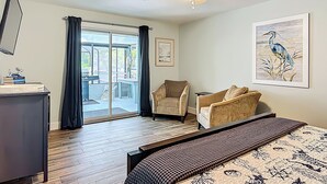 Ein Schlafzimmer mit Bett, Stuhl, Schreibtisch, Deckenventilator und einem Gemälde.