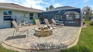 Eine Terrasse mit Gartenmöbeln, einer Feuerstelle und einem überdachten Sitzbereich.