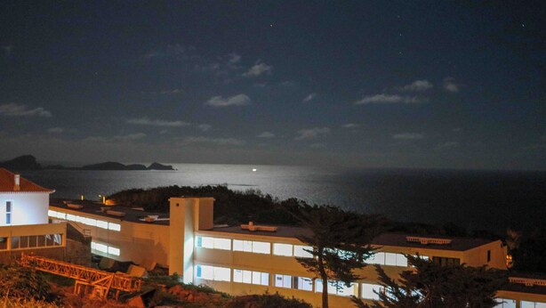 Un hôtel situé sur la côte, composé de plusieurs bâtiments, doté d’un pont et offrant une vue sur la mer.
