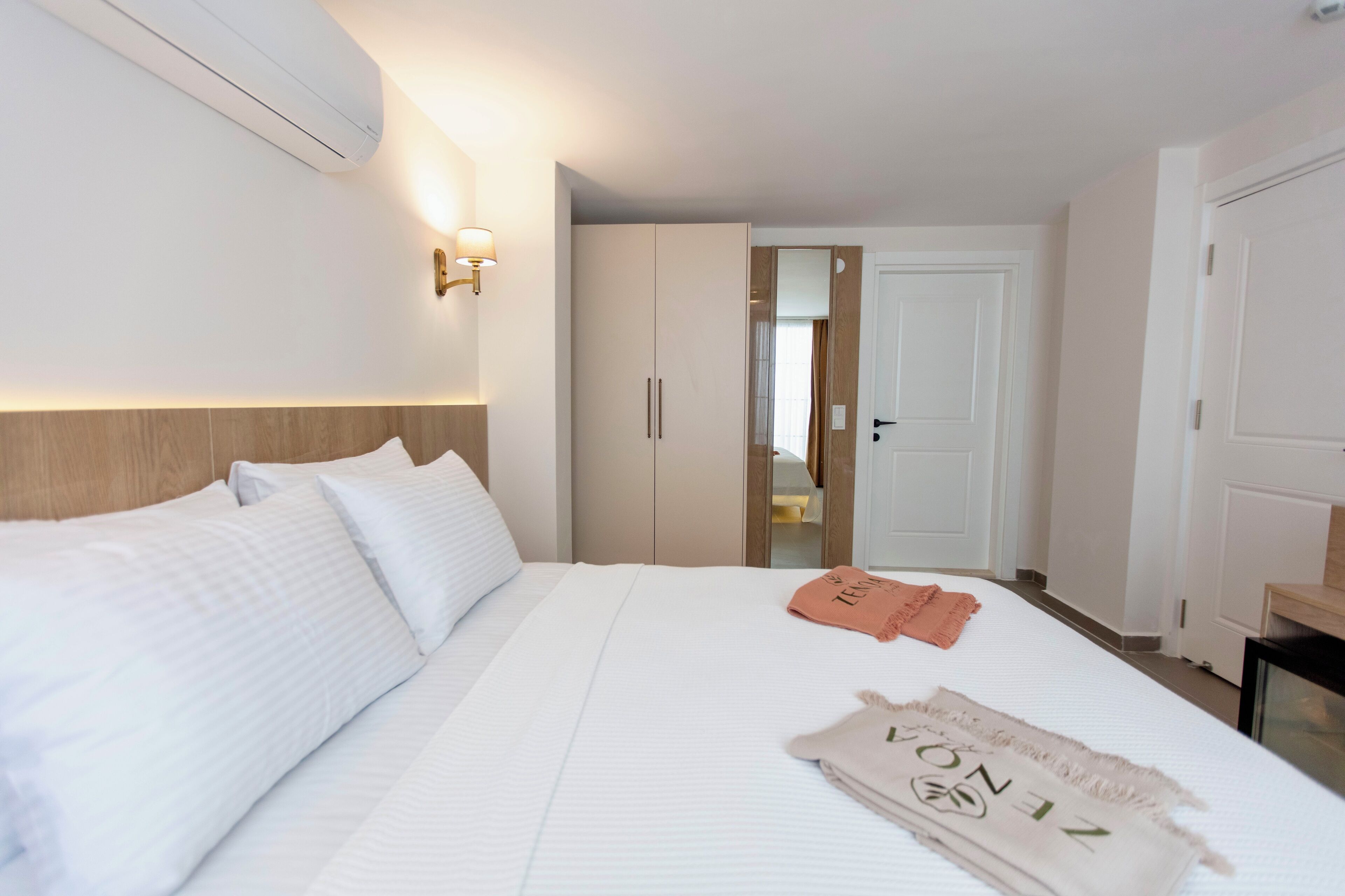A hotel room with a large bed, a wardrobe, a mirror, and a door leading to another room.