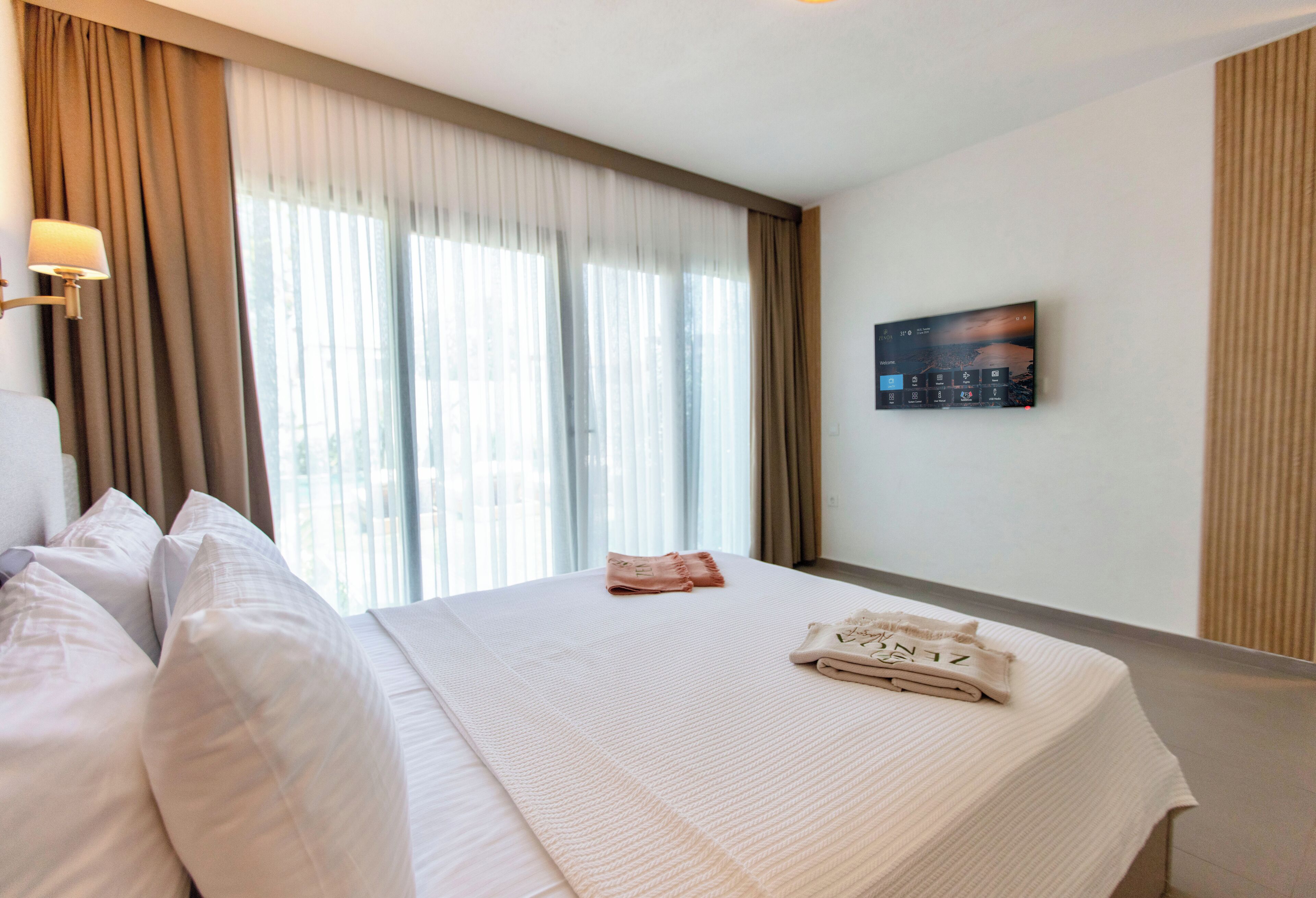 Une chambre d’hôtel avec un grand lit, un téléviseur à écran plat et une fenêtre avec des rideaux.