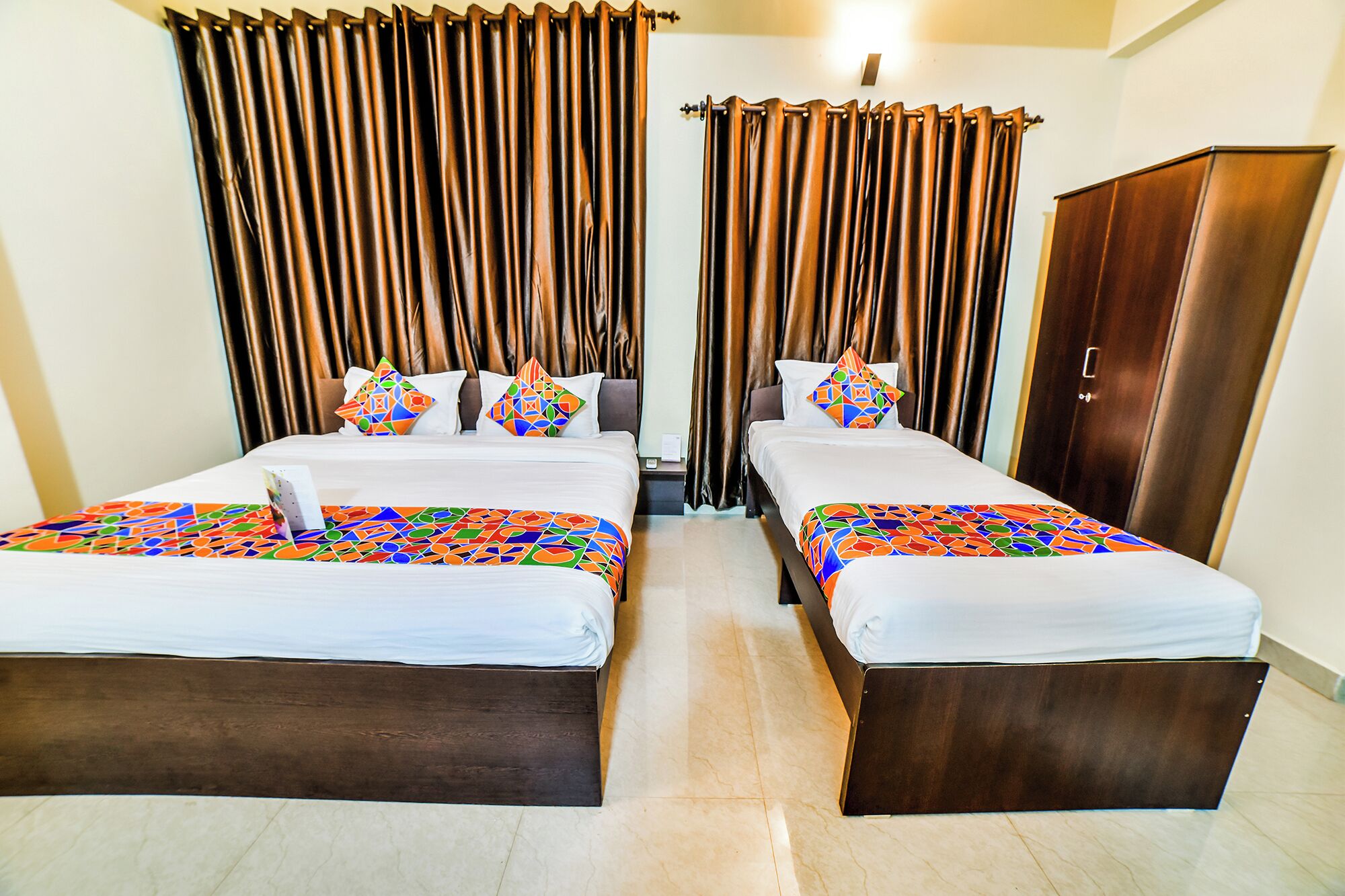 A hotel room with two beds, a wardrobe, and curtains.