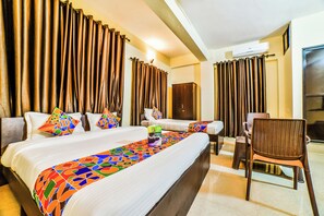 A hotel room with two beds, a wardrobe, a chair, and a large window with curtains.