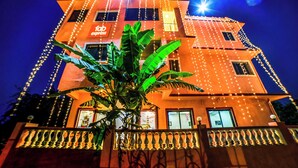 Un edificio de varios pisos con un letrero 'fab express', luces de adorno y un balcón con barandilla.