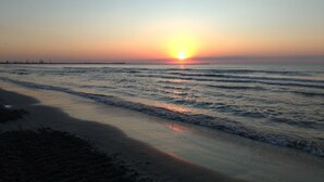 Ein Strand bei Sonnenuntergang, sanfte Wellen umspülen das Ufer.