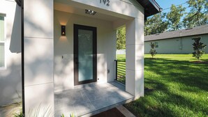 Une maison moderne avec le numéro « 192 » au-dessus de la porte, une porte en verre et un petit porche avec un paillasson.