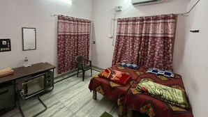 Ein Zimmer mit einem Bett, einem Schreibtisch, einem Stuhl und einer Klimaanlage.