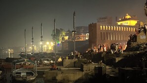 Nachtansicht einer Flussuferanlage mit Booten, Menschen und einem markanten Gebäude mit Kuppel.