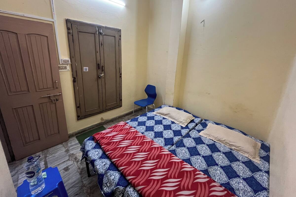 Habitació petita i poc moblada amb un llit individual, una cadira i un armari.