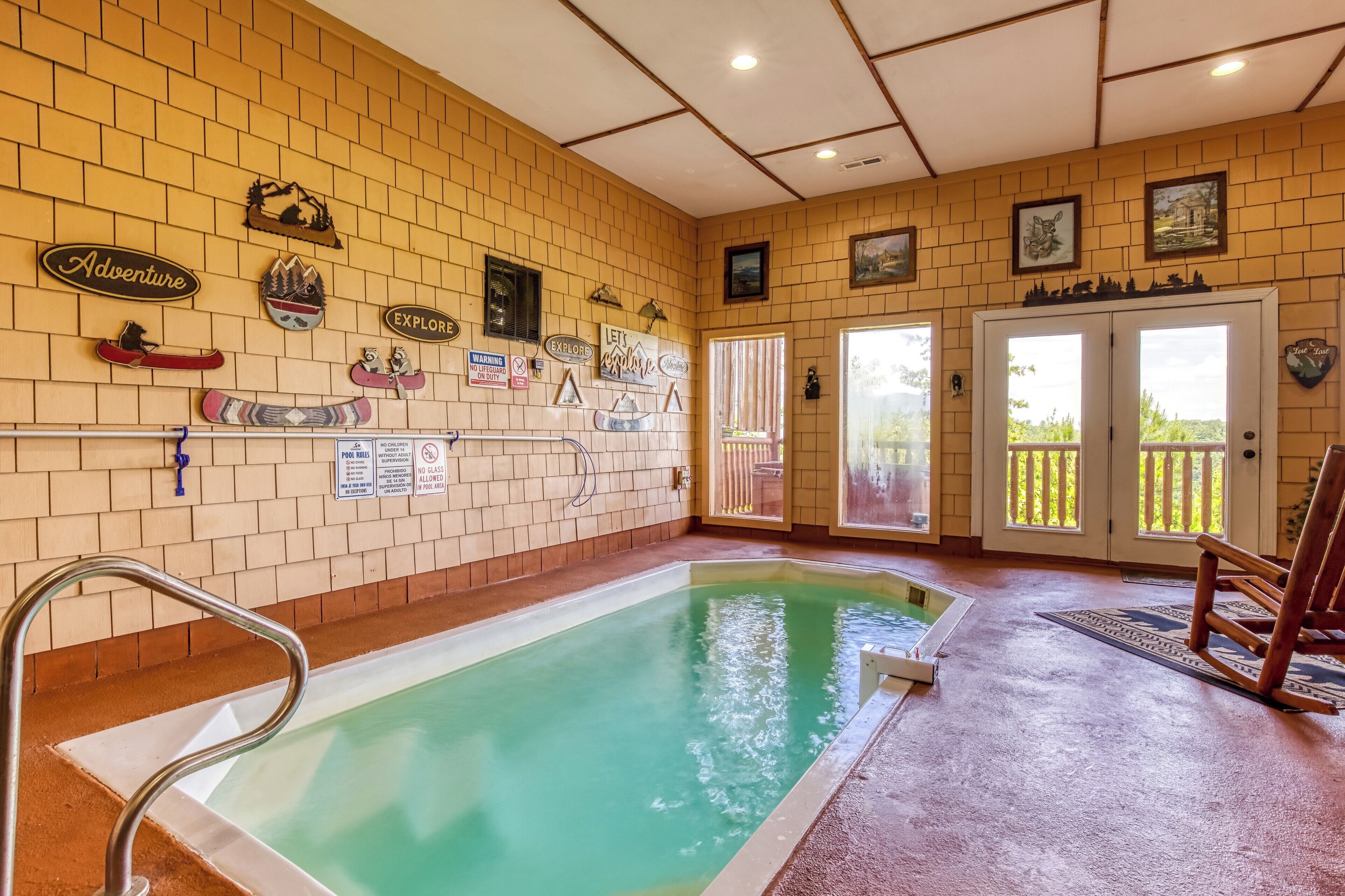 Una piscina interior amb paret de maó, diversos senyals i una cadira de fusta.