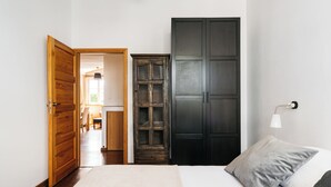 Een slaapkamer met een bed, een kledingkast en een deur naar een andere kamer.