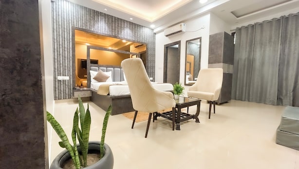 A modern living room with a sofa, armchairs, a coffee table, and a potted plant.