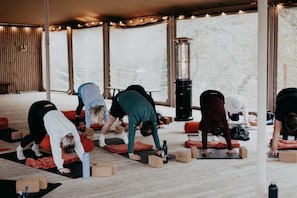A group of people performing yoga in a room with wooden flooring, mats, and blocks. - Tree Top - 1-Bed Sea View Apartment with Balcony at Tors Park (Lynmouth)