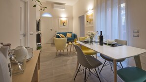 Una sala de estar moderna con un sofá, una mesa de comedor con sillas y una cocina al fondo.