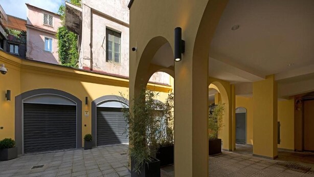 Un patio con dos puertas de garaje cerradas, plantas en macetas y suelo de baldosas.
