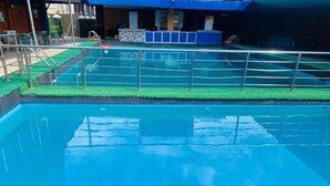 A swimming pool with a metal railing and a green artificial turf area. - Vienna International Hotel (Asaba)